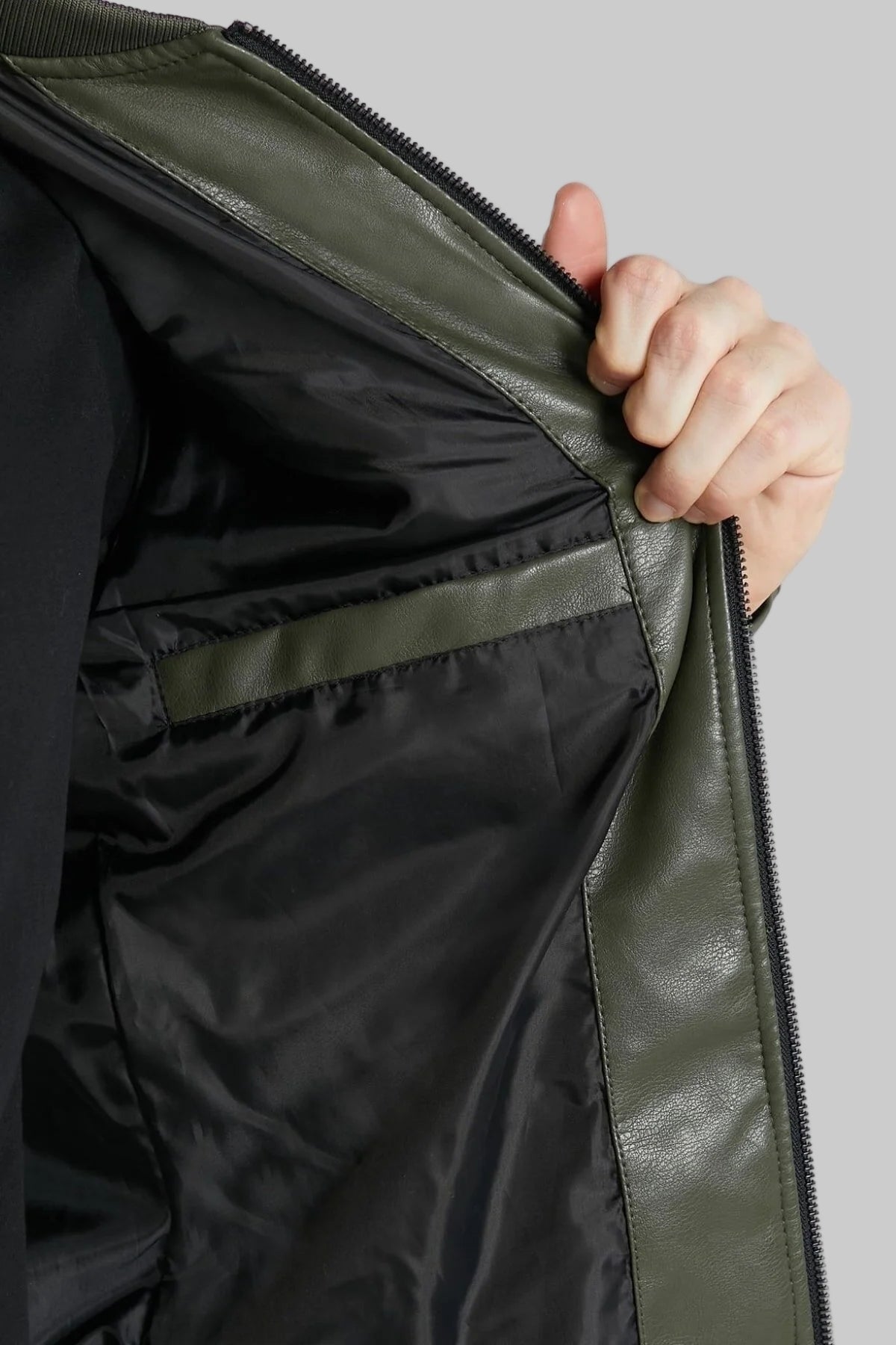 Close-up of a person opening a black jacket with a zipper on a light gray background