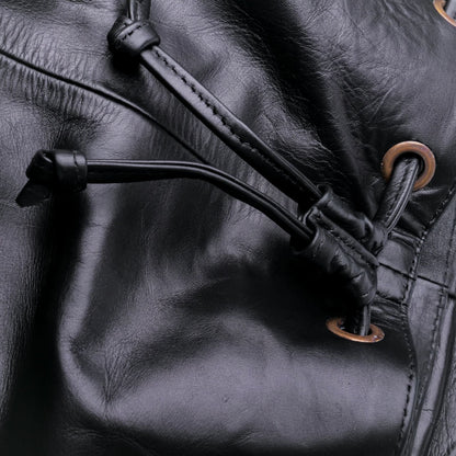 Close-up of a black leather boot with drawstring and metal eyelets.