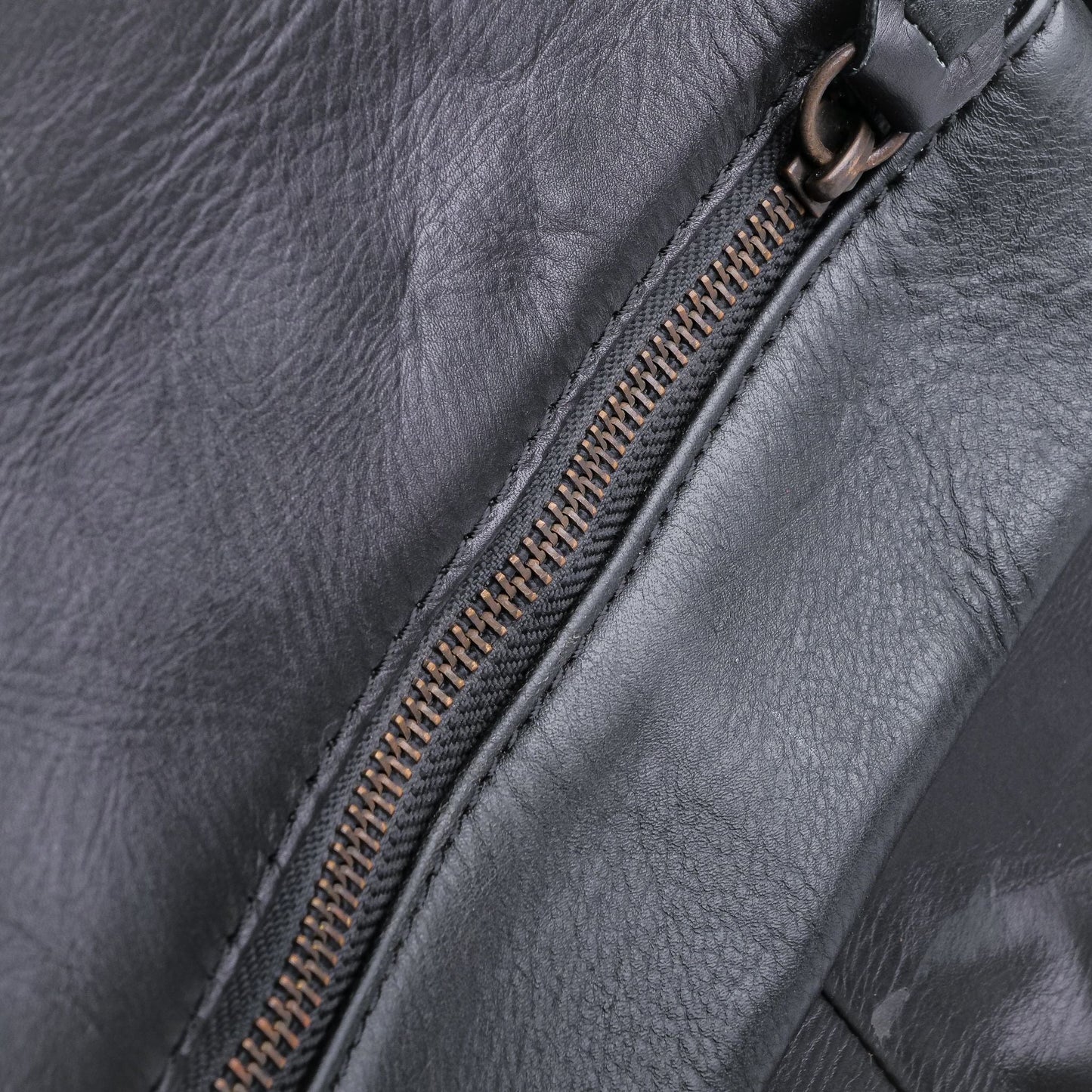 Close-up of a dark gray leather bag with a zipper