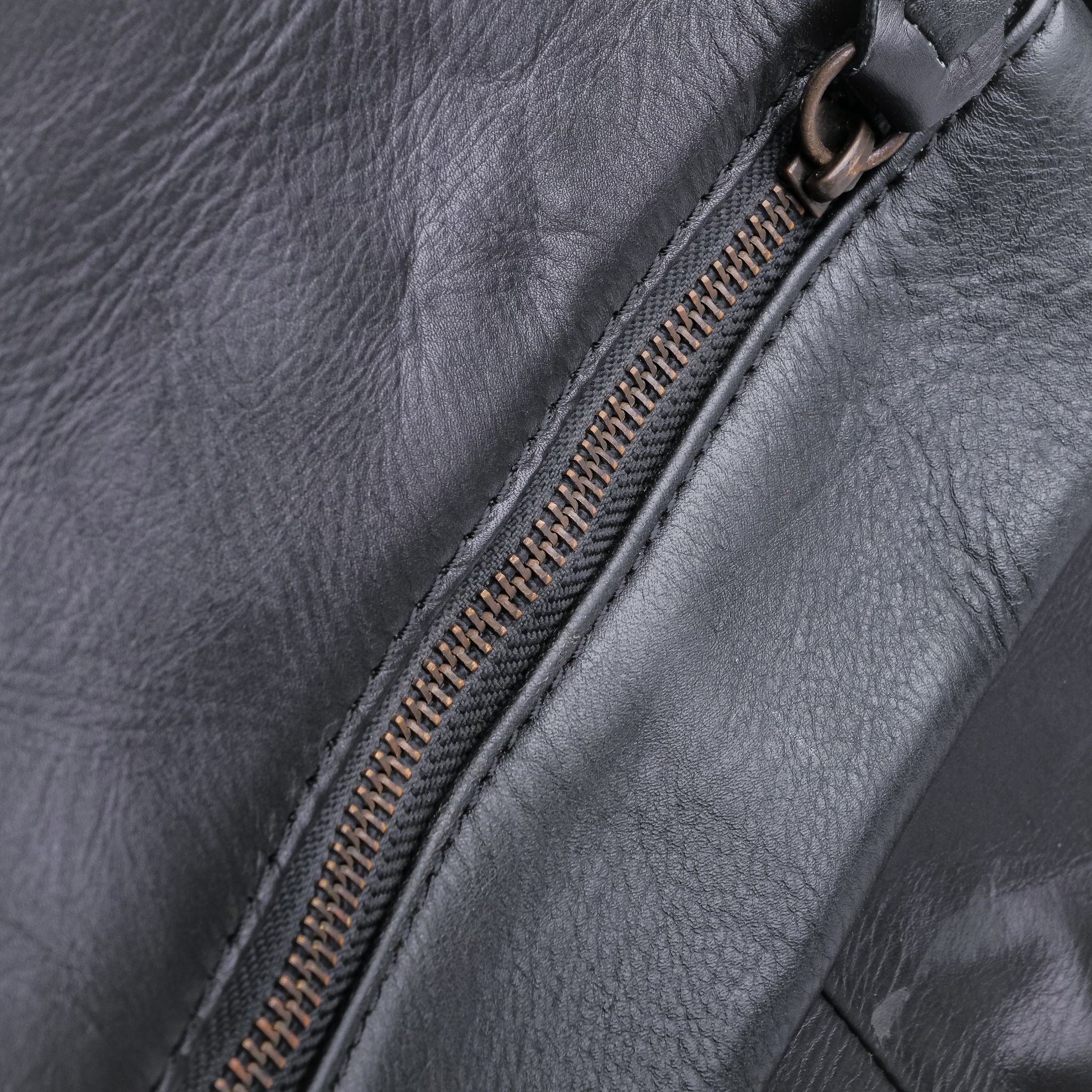 Close-up of a dark gray leather bag with a zipper