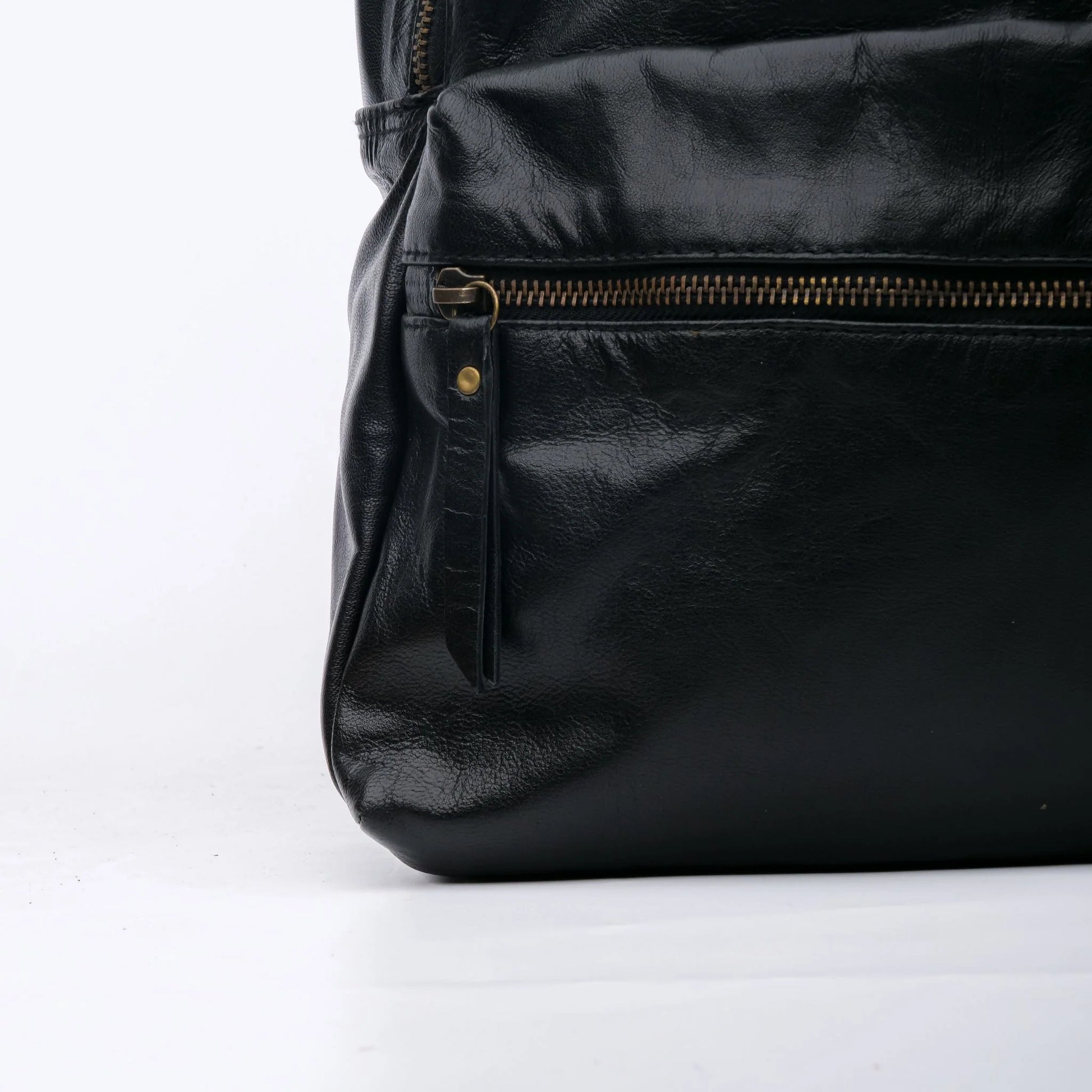 Black leather bag with gold zipper on a white background