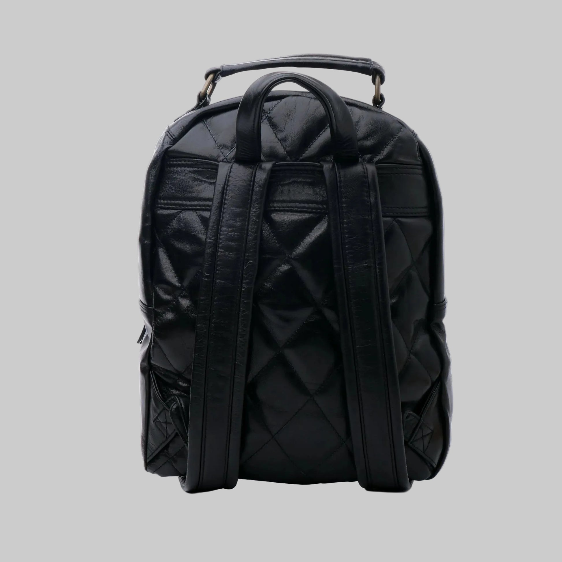 A black quilted faux-leather backpack with dual top handles and wide shoulder straps, shown from the back on a white studio background.