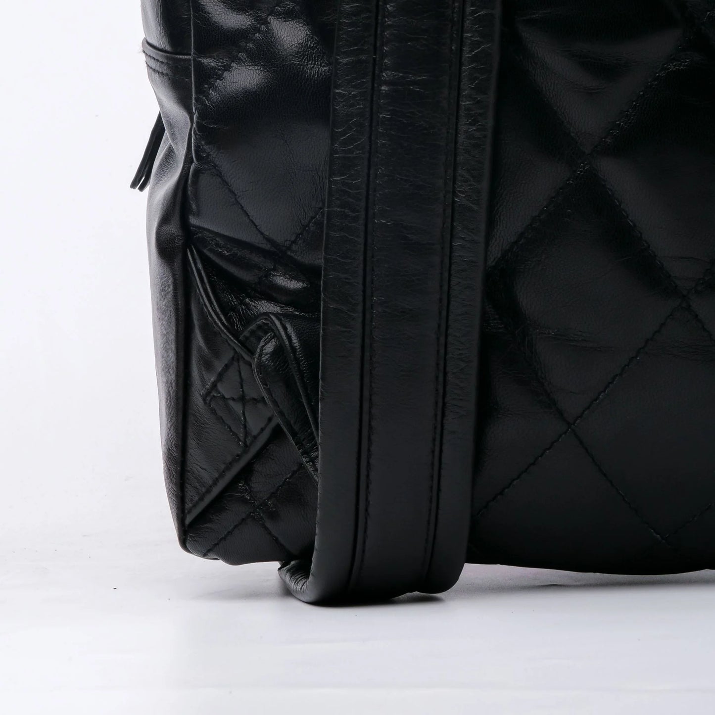 Close-up of a black quilted backpack on a white background