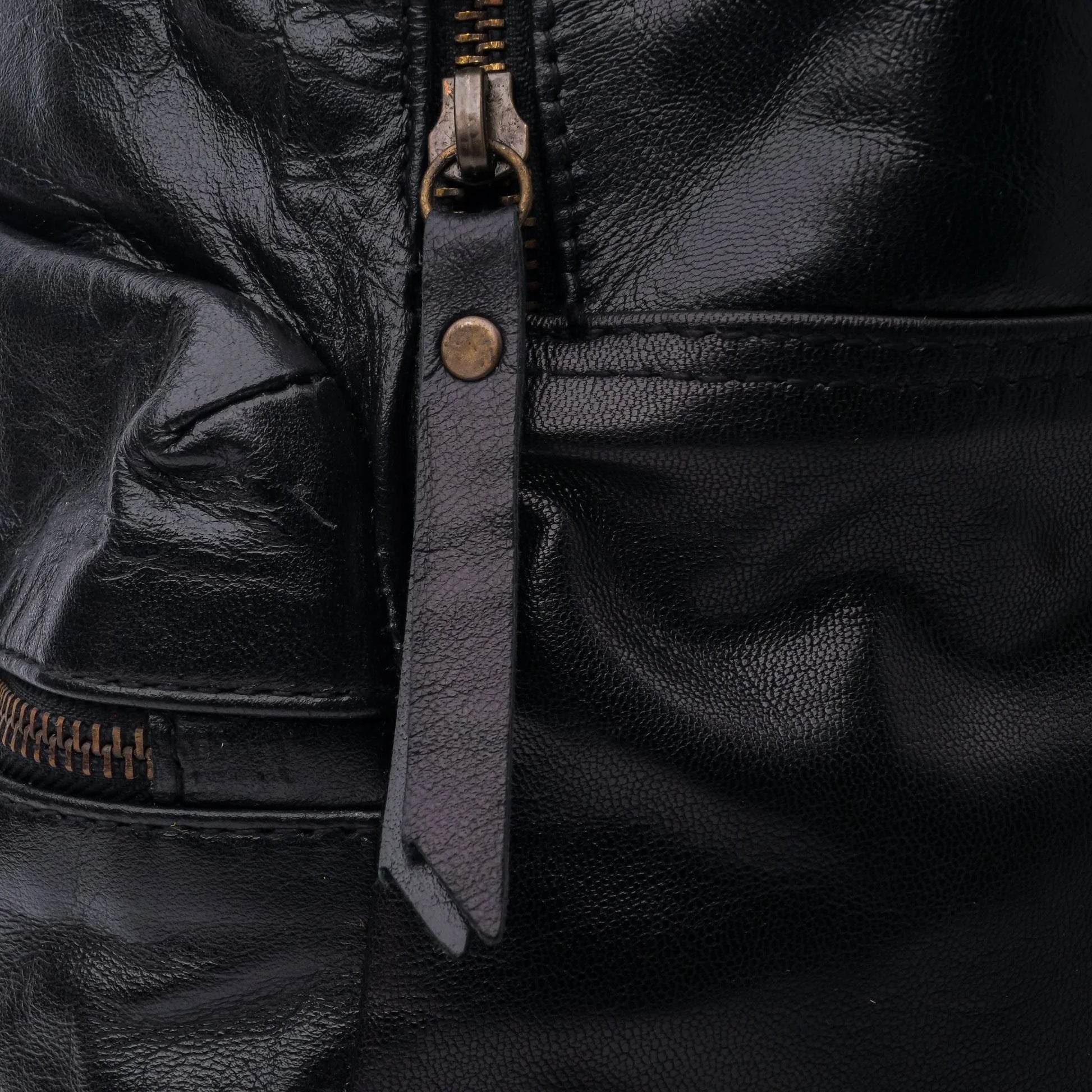 Close-up of a black leather jacket with a zipper and strap detail.