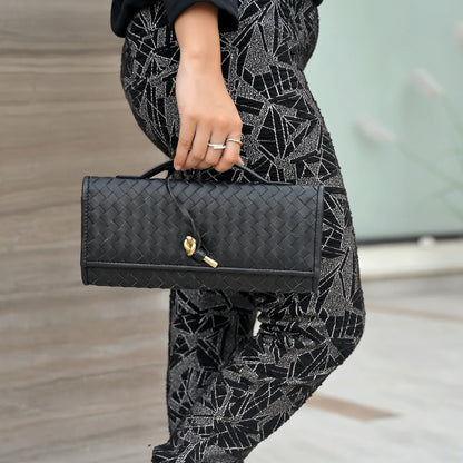 Person holding a black handbag with a patterned outfit
