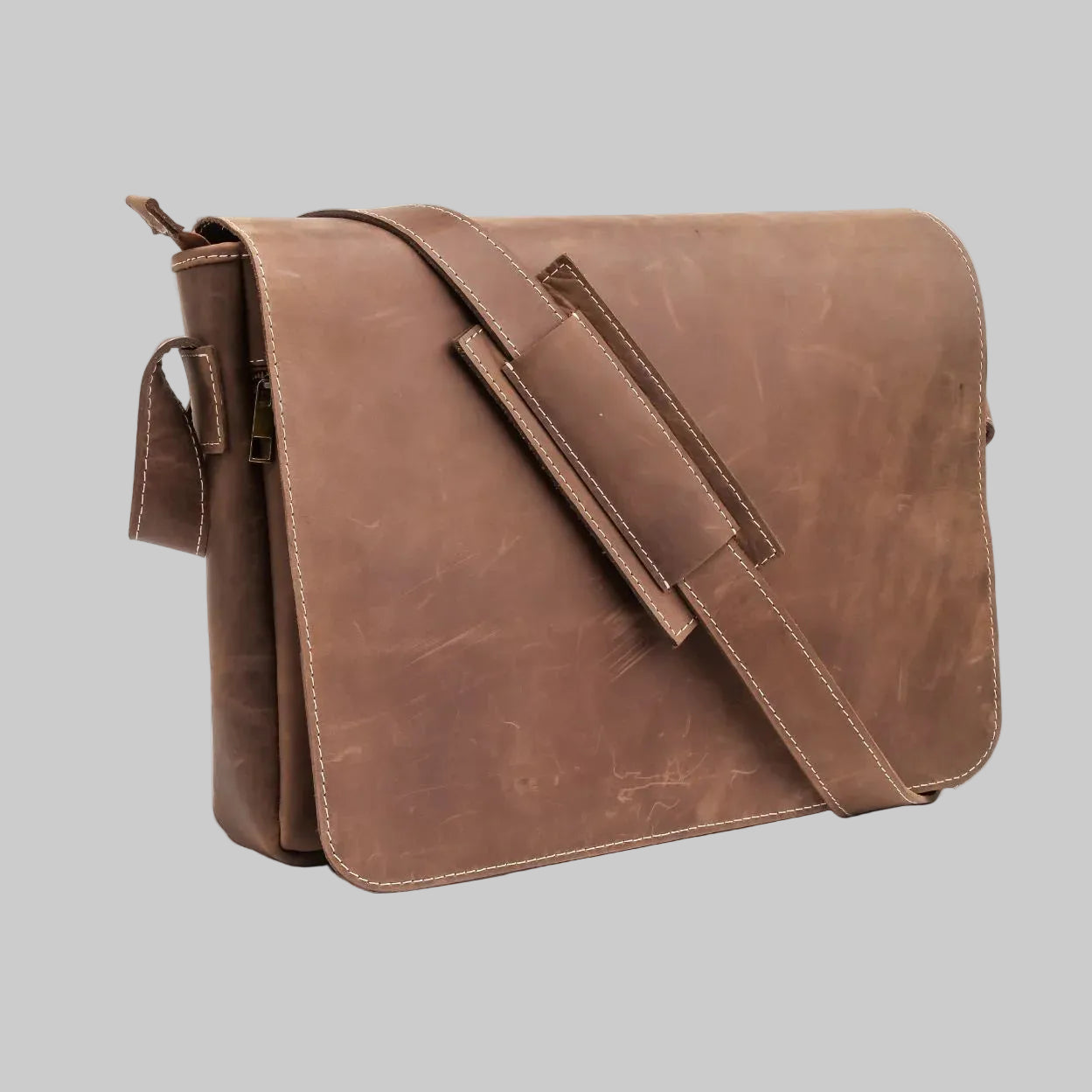 A brown distressed leather messenger bag with a wide adjustable shoulder strap and a zippered side pocket, shown on a plain white background.