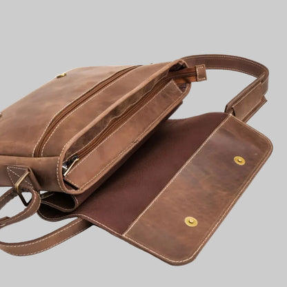 A brown leather shoulder bag with a flap closure, shown partially open to reveal the interior lining and a zippered compartment, on a white background.