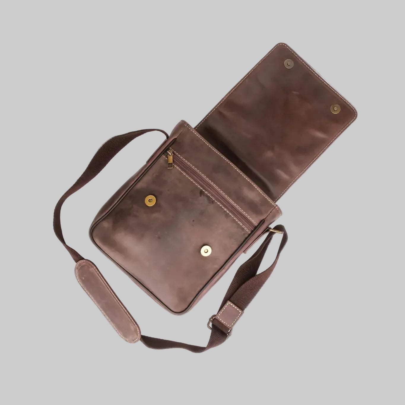 Brown leather bag with a strap on a white background