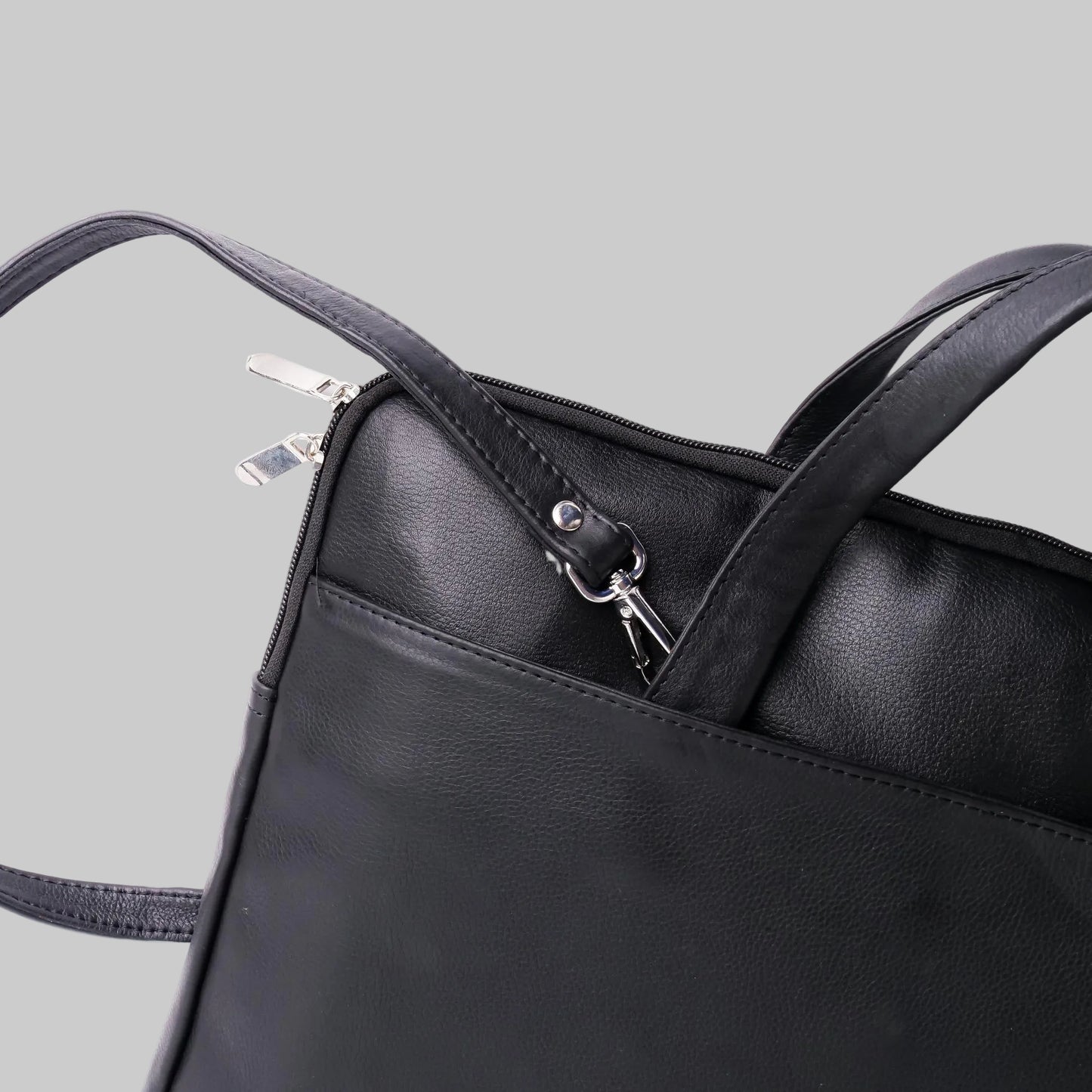 Black leather handbag with a clear plastic bag inside on a white background