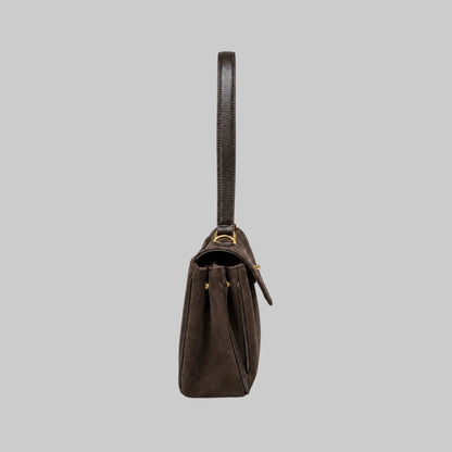A dark brown suede shoulder bag with a single leather strap and gold-tone hardware, shown from a side profile view against a plain white background.