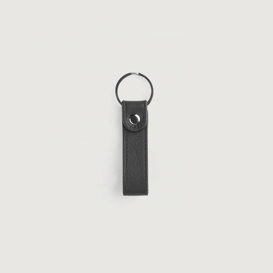 Black leather keychain with metal ring on a light gray background