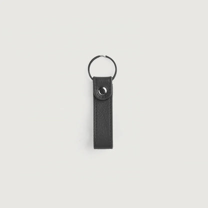 Black leather keychain with metal ring on a light gray background