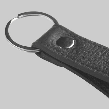 Black leather keychain with metal ring on a light gray background