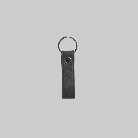 Black leather keychain with metal ring on a light gray background