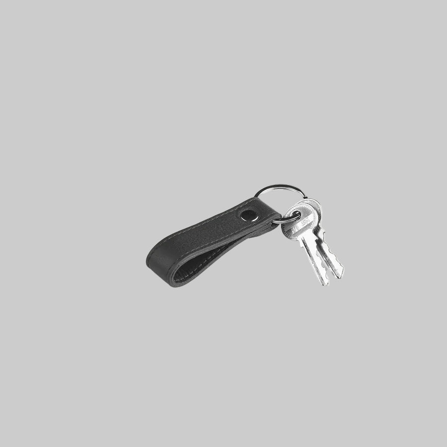 Black leather keychain with keys on a light gray background