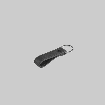Black keychain with a strap on a light gray background
