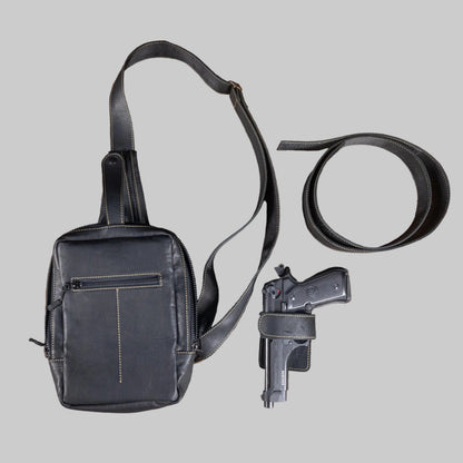 Black leather bag, gun, and belt on a wooden surface