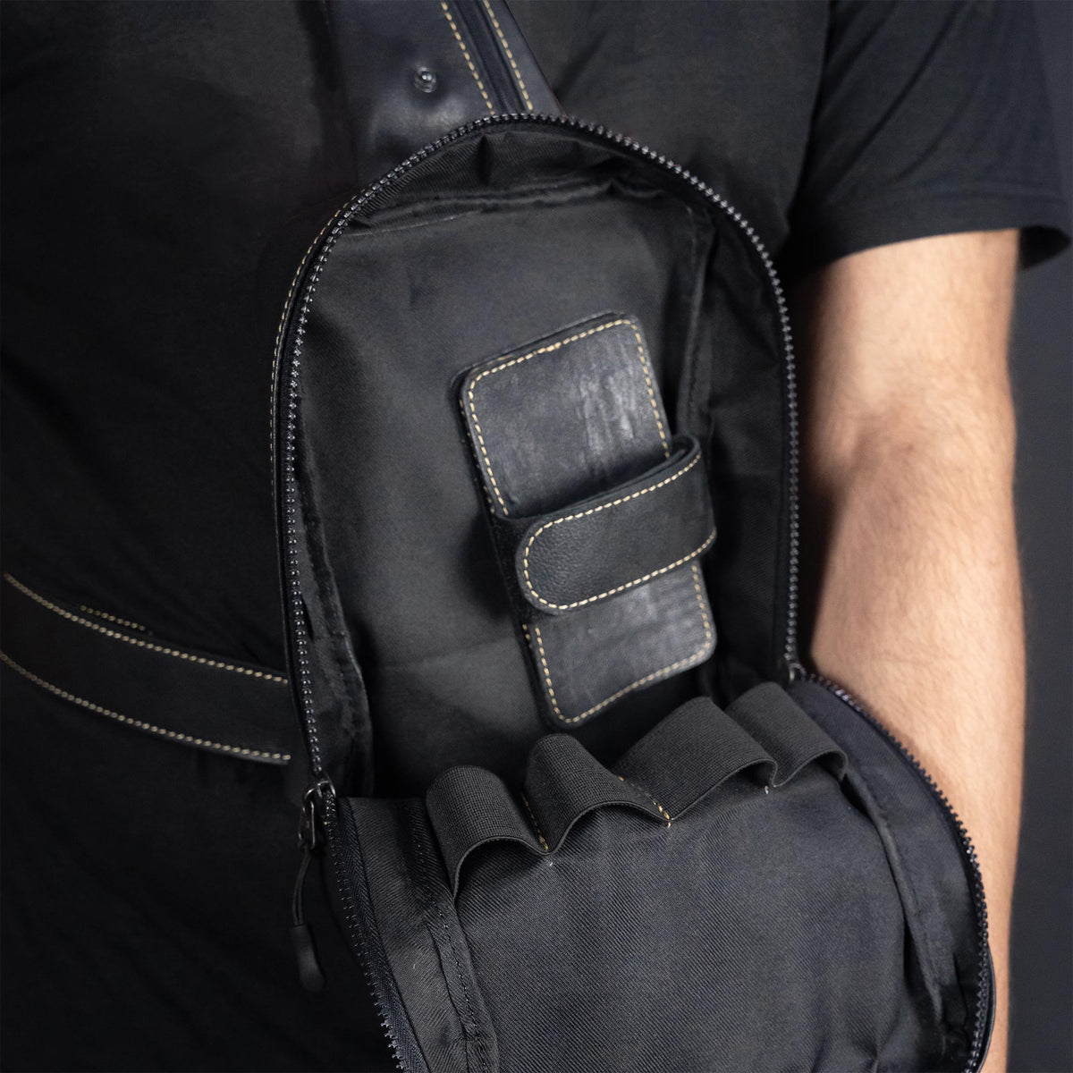 Black backpack with a pocket on a person against a dark background