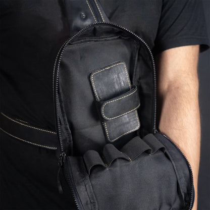 Black backpack with a pocket on a person against a dark background