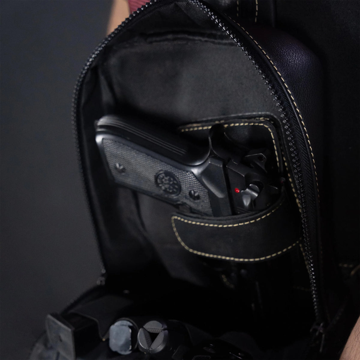 Black backpack with a gun inside on a dark background