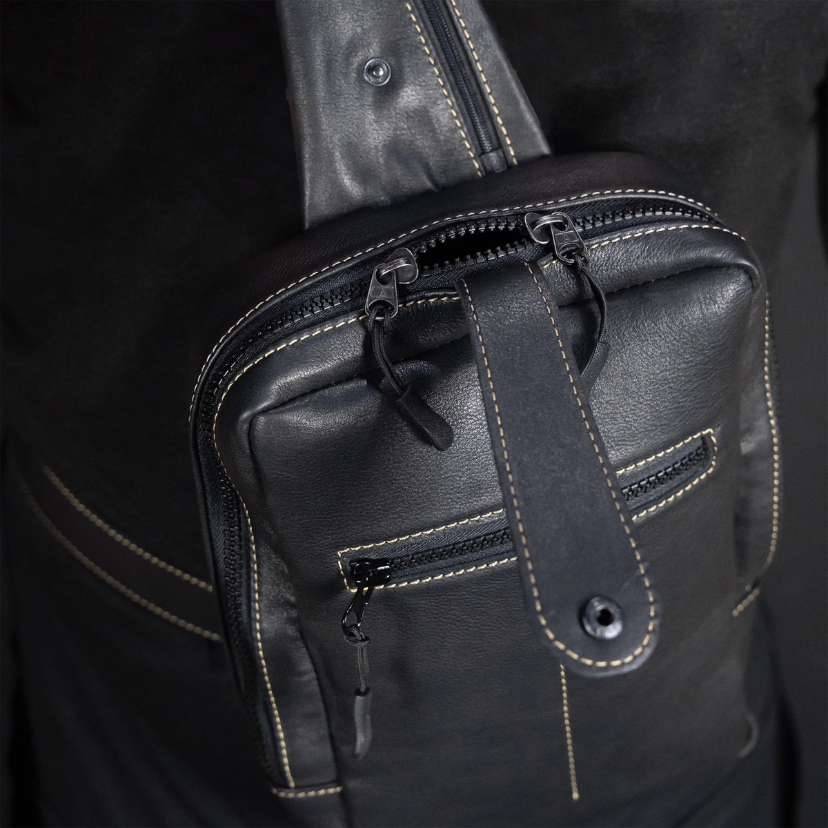 Close-up of a black leather bag with zippers on a dark background