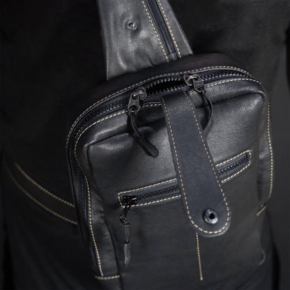 Close-up of a black leather bag with zippers on a dark background