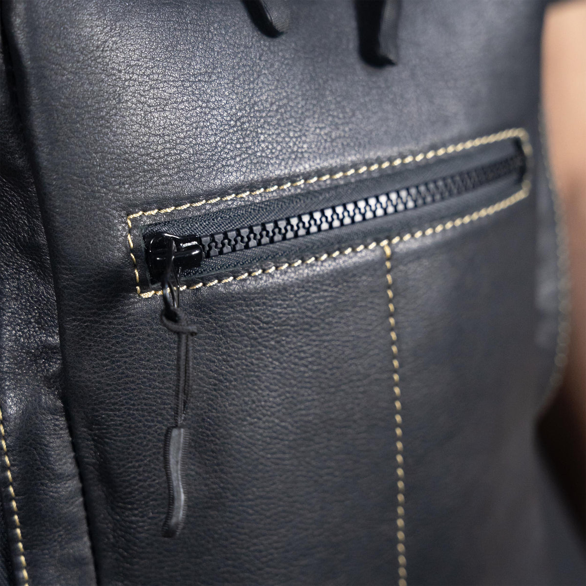Close-up of a black leather backpack with a zipper