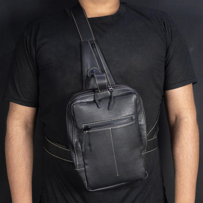 Person wearing a black leather crossbody bag against a dark background
