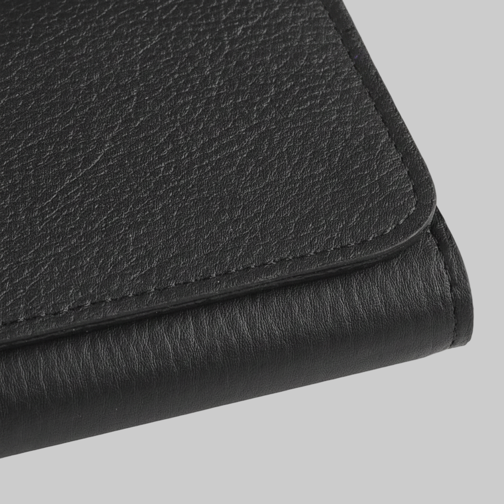 Close-up of a black leather clutch on a light gray background