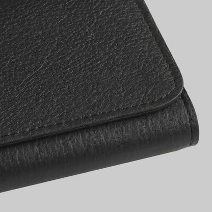 Close-up of a black leather clutch on a light gray background