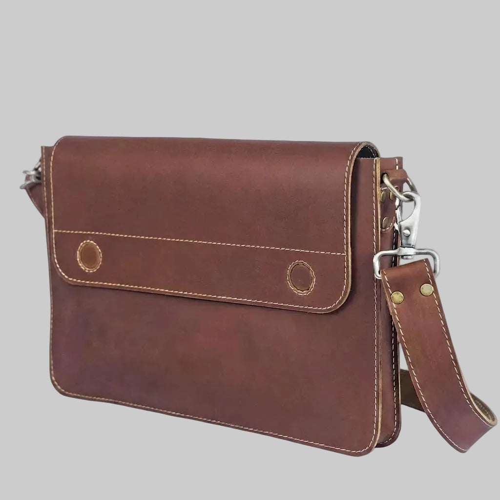 A brown leather crossbody bag with a front flap pocket, contrast stitching, and a detachable shoulder strap with silver metal hardware, shown on a plain white background.
