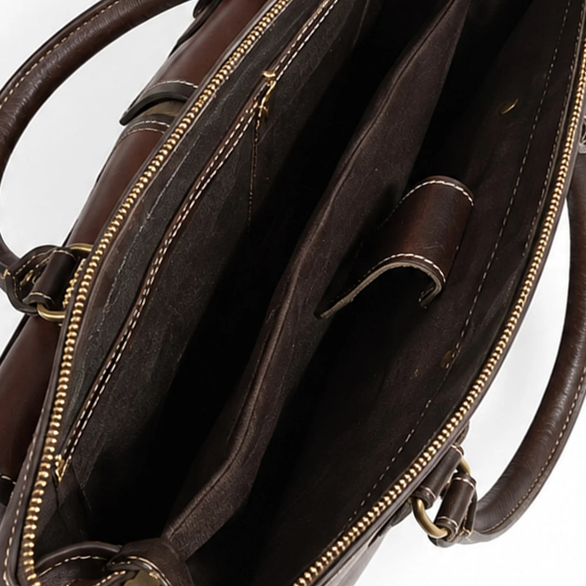 Close-up of the interior of a dark brown leather handbag, showing the spacious compartments, gold-tone zippers, and contrast stitching against a white background.