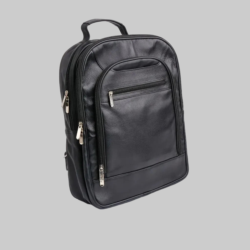 A black faux-leather backpack with multiple zippered compartments and silver-tone hardware, photographed on a seamless white background.