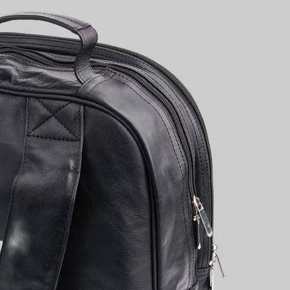 Close-up of a black leather backpack with zippers on a white background