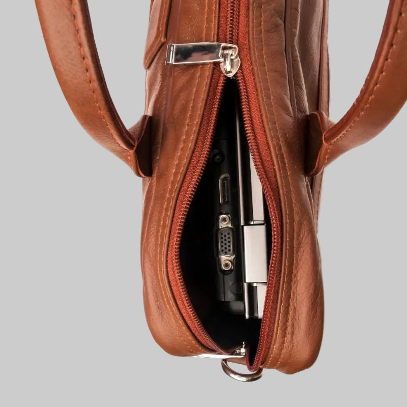 Brown leather bag with a zipper, containing electronic devices on a white background