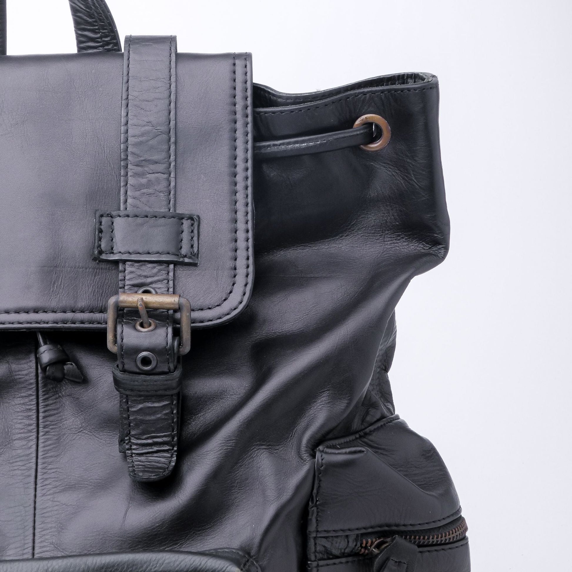 Close-up of a black leather bag with a strap on a white background